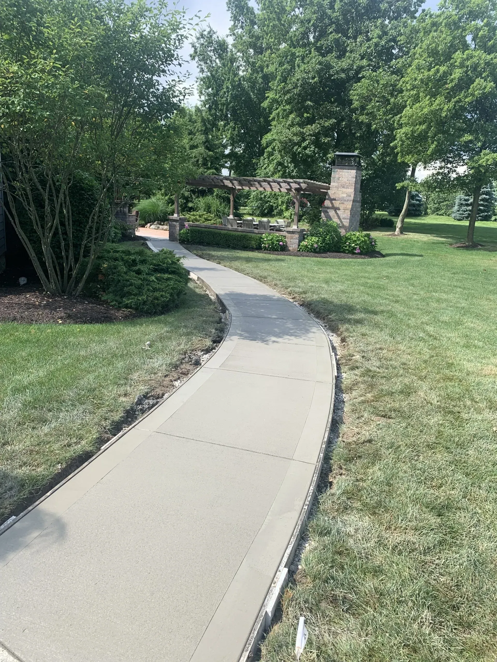 Curved concrete walkway through a landscaped yard